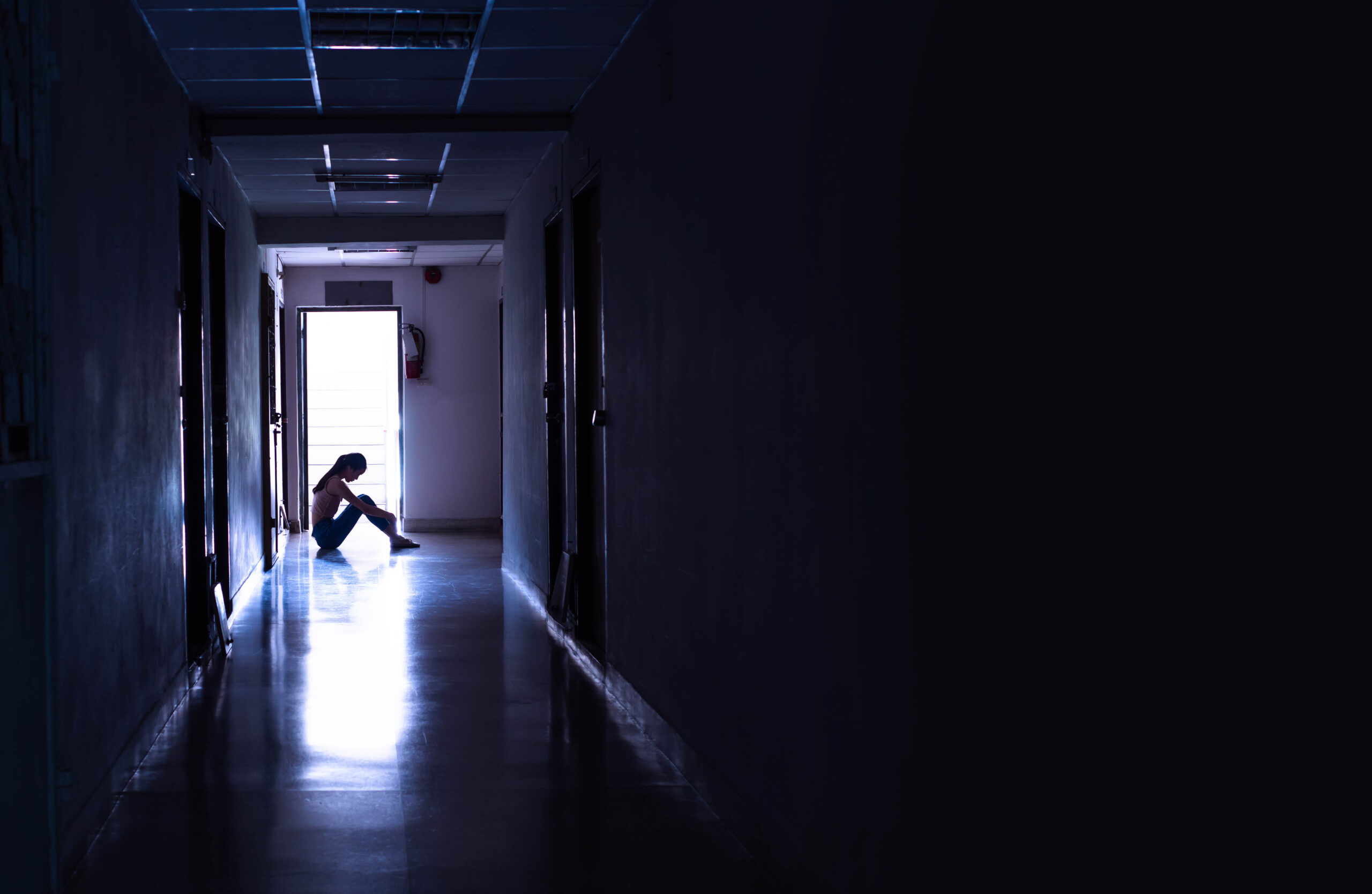 woman needing spiritual healing for depression sitting in dark hallway